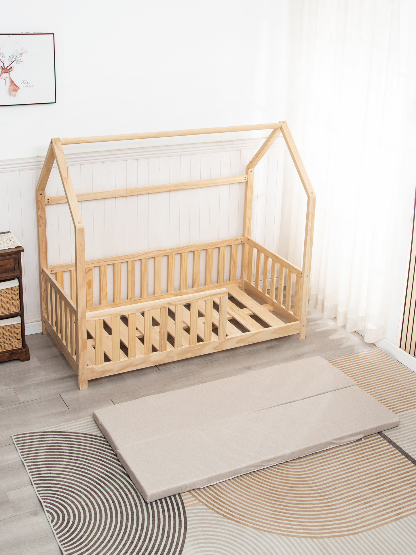 Wooden crib with a mattress on a wooden floor in a room.