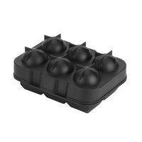 Black 6-cavity round ice ball mould, top closed, star-shaped vents visible between dome cavities, angled view