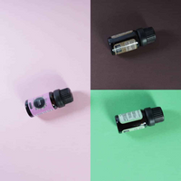 Three dark amber 10ml essential oil bottles lying on their sides across split pink, brown, and green backgrounds, overhead…