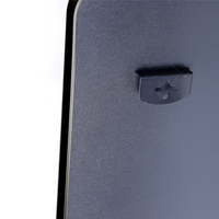 Close-up of black mirror rear panel showing a single plastic mounting clip with cross-shaped keyhole slot near the left edge