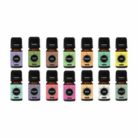 14 small amber glass essential oil bottles in two rows, each with colourful labels including lavender, tea tree, cinnamon,…