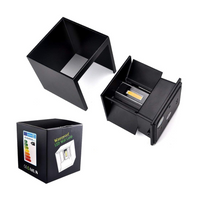Black cube LED wall lamp disassembled showing housing shell separated from base unit with visible COB LED chip, beside ret…