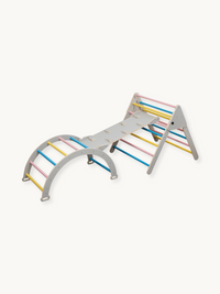 Grey wooden kids climbing set with triangle frame, arch, and ramp connected, featuring pink, blue, and yellow rungs, angle…