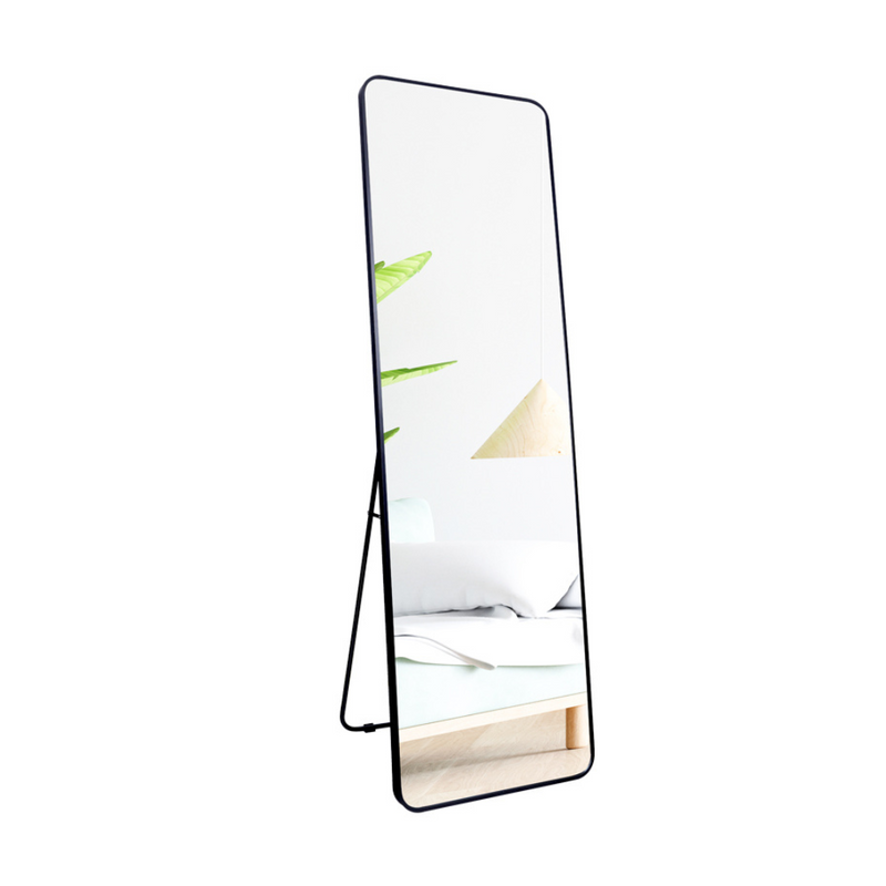 Black full-length floor mirror with rounded corners and thin brushed aluminium frame, shown freestanding with kickstand, a…