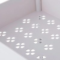 Close-up of white metal shelf base showing flower-shaped cutout ventilation pattern across the perforated tray surface