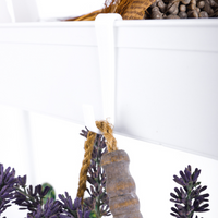 Close-up of white metal rack handle bracket with jute-tied wooden ornament hanging below, artificial lavender sprigs and p…