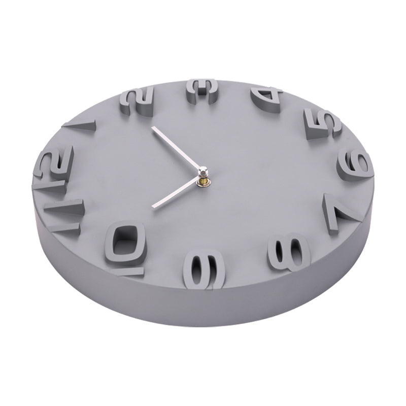 Grey round wall clock photographed from above at an angle, showing 3D raised numerals and silver hands against smooth matt…