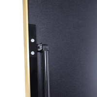 Close-up of black metal bracket and support rod attached to back of dark grey MDF board, with gold brushed aluminum frame…