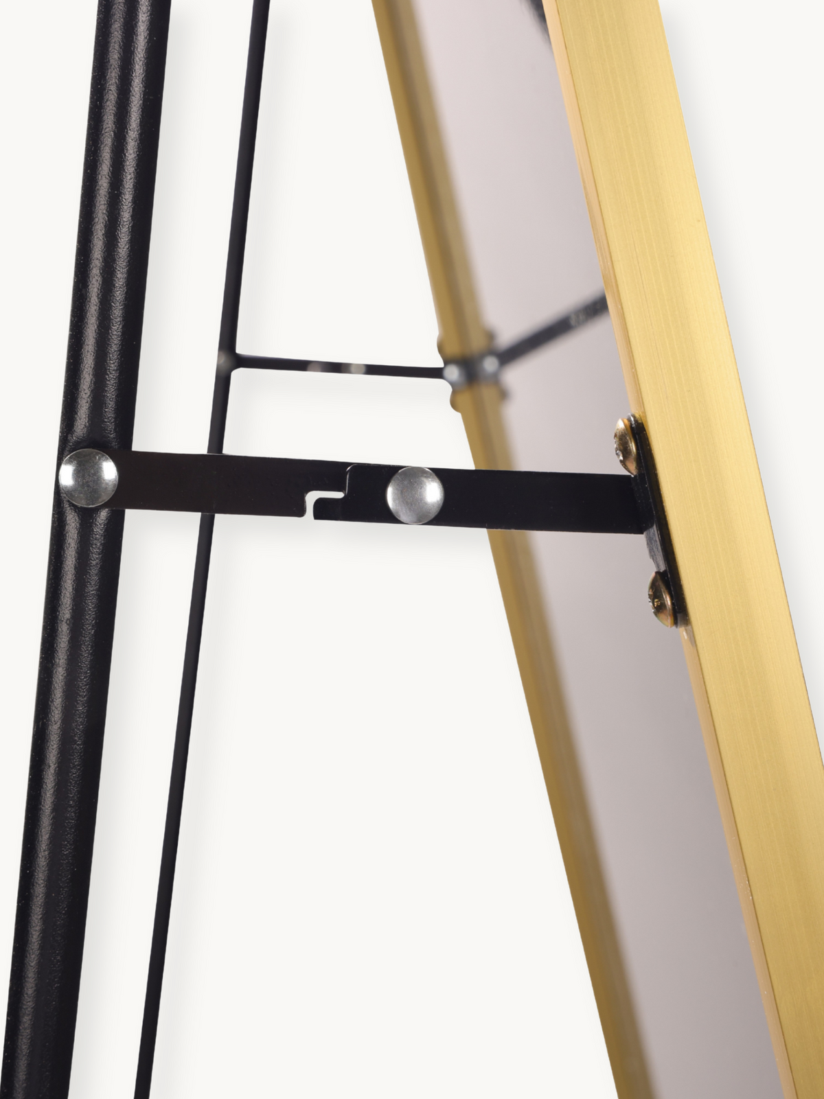 Close-up of black metal freestanding bracket with silver rivets connecting to gold aluminium frame back, showing easel-sty…