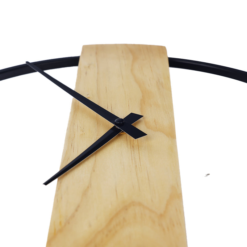 Close-up of black clock hands and centre pivot mounted on a light natural wood panel with visible grain