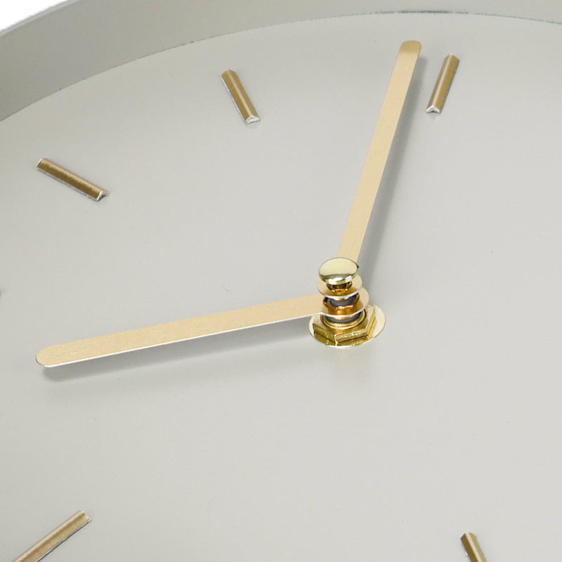 Close-up of pale green clock face showing gold-tone hour and minute hands, brushed gold dash markers, and polished centre…