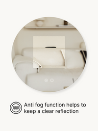 Round LED bathroom mirror detail showing anti-fog touch icon and clear reflection of a cream sofa and shelves in a living…