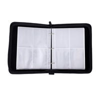 Black zippered trading card binder open flat, showing two clear 3-pocket pages on a ring mechanism, empty and ready to fill