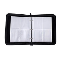 Black zip-close trading card binder open flat, showing empty 3-ring clear plastic card sleeves with 4-pocket pages, overhe…