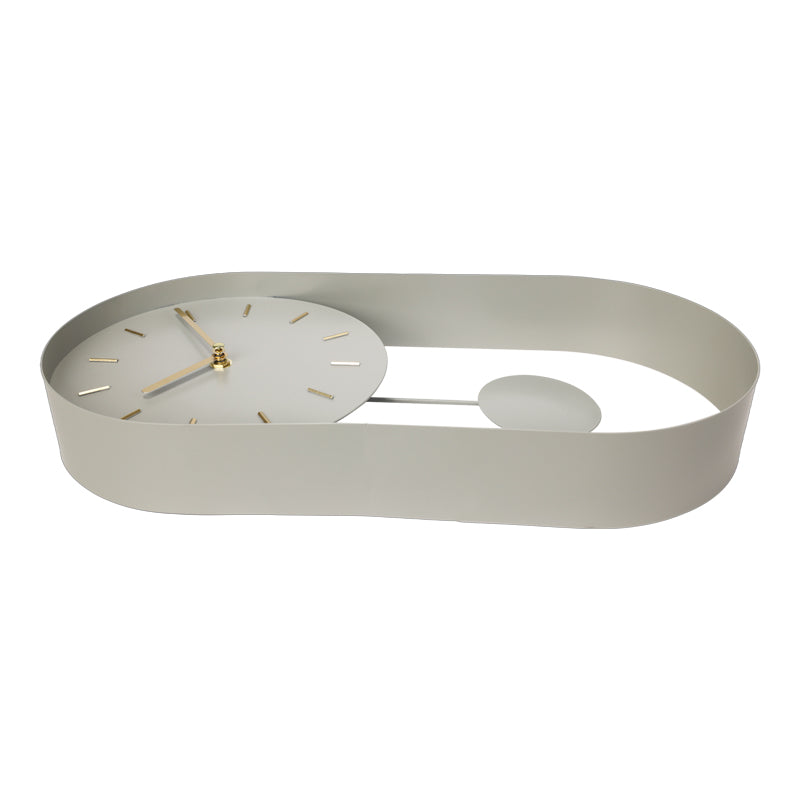 Pale green iron pendulum wall clock viewed from below at an angle, showing oval loop frame base and spherical bob on white…