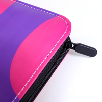 Close-up of purple and pink faux leather card binder corner showing black zipper and pull tab detail, white stitching visible