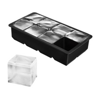 Black silicone large-cube ice tray filled with frozen cubes, one clear square ice cube displayed separately in front, whit…