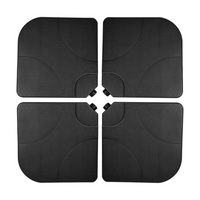 Four black plastic parasol base tiles arranged in a 2x2 grid, showing curved cutouts at centre where pole fits, top-down view