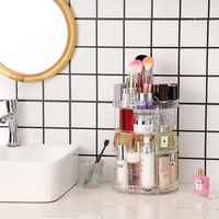 Clear 3-tier rotating makeup organiser on bathroom counter beside sink, loaded with perfumes, brushes, skincare and lipsticks