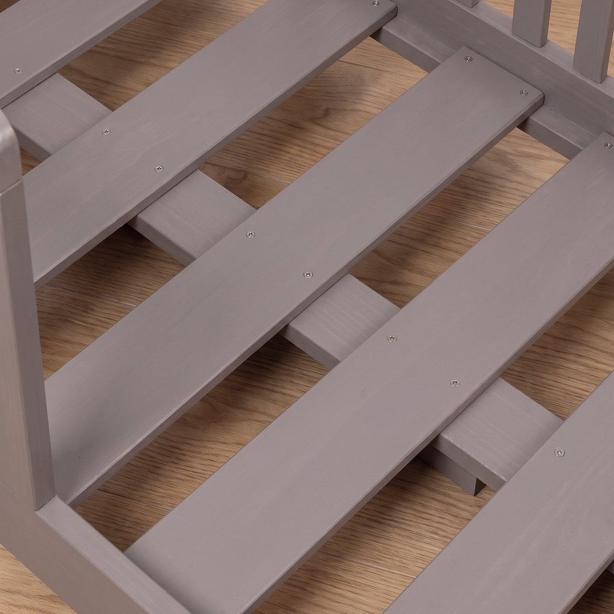 Close-up of grey painted wood bed slats and frame joints with visible screws, showing slatted base construction detail