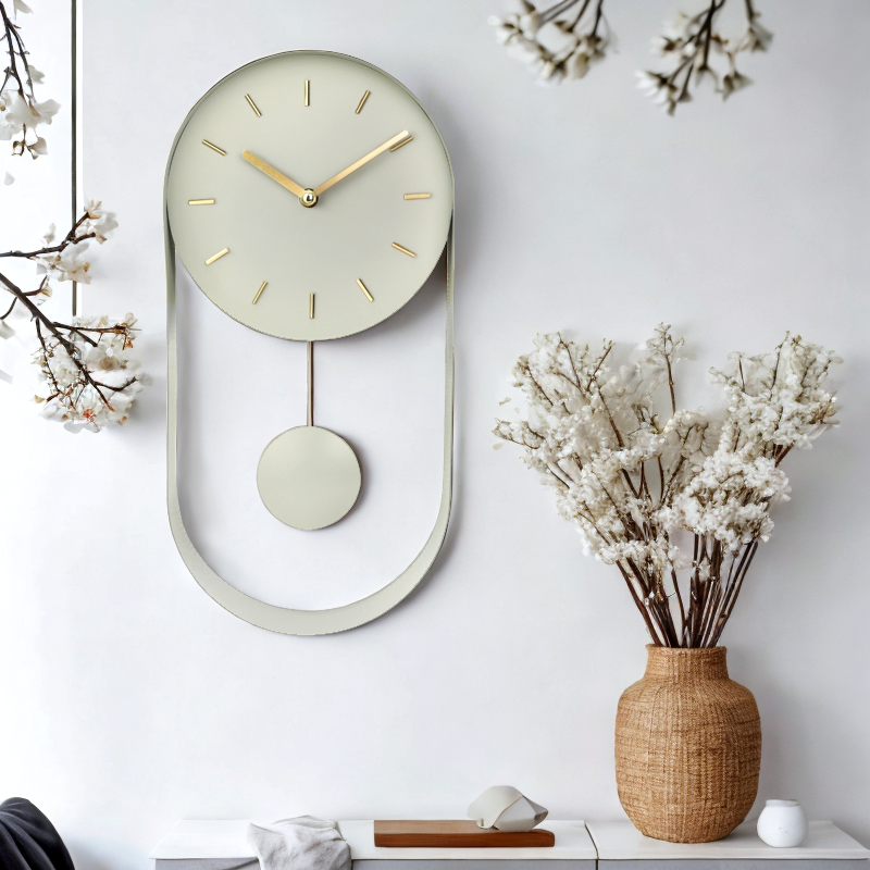 Pale green pendulum wall clock on white wall above a shelf with woven vase of white blossom branches, lifestyle setting