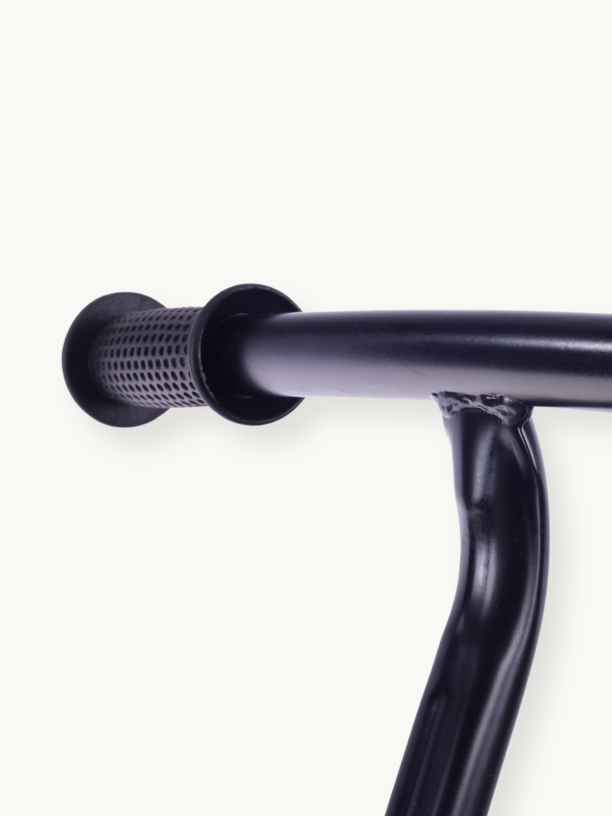 Close-up of black rubber handlebar grip end on dark steel handlebar, showing textured perforated pattern and stem weld joint