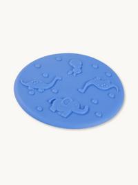 Blue balance disc angled view showing raised elephant, dinosaur, lizard, and bird figures on textured surface
