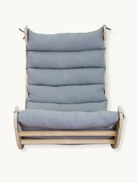 Front-on studio view of natural wood climbing arch rocker with grey padded cushion fitted across seat and high backrest