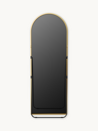 Front view of full-length arched mirror showing black metal easel stand and base rail against white background, gold frame…