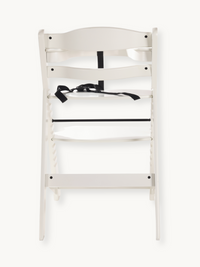 White wooden baby high chair rear view showing black safety harness with buckle and horizontal footrest bar detail.