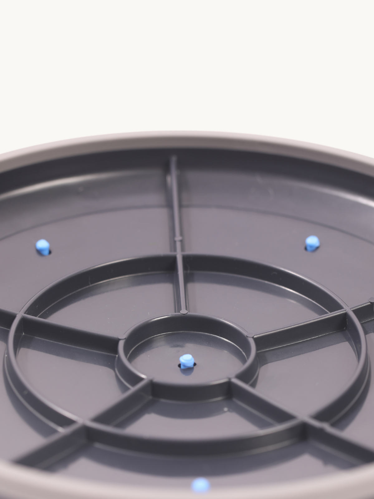 Dark grey balance disc bottom view showing central spoke frame and three blue anti-slip studs on white background