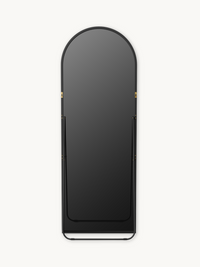 Front view of black aluminium arched full-length mirror showing gold wall-mount brackets mid-frame and curved base stand,…
