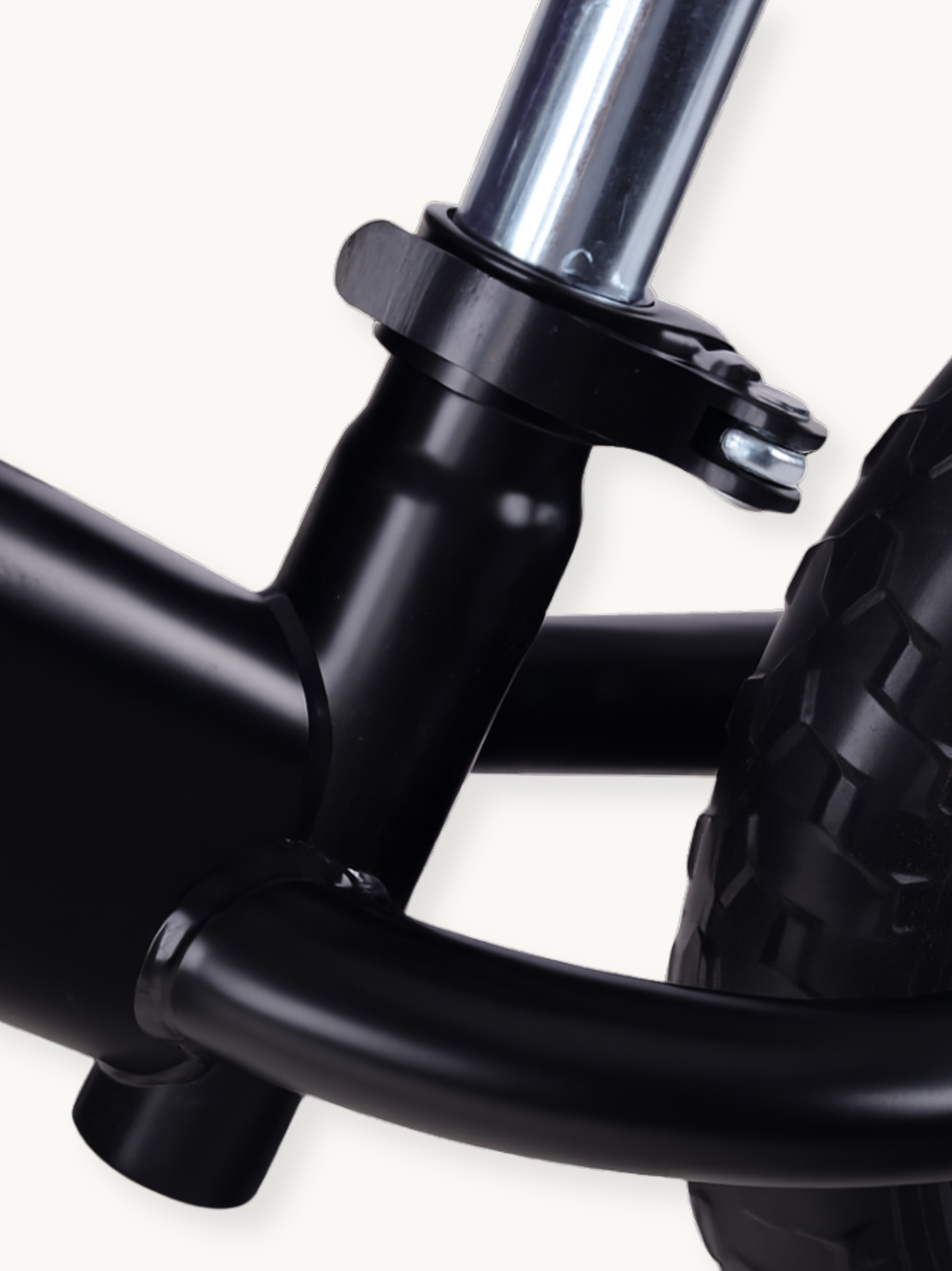 Close-up of black steel fork crown and headset junction on New Speed balance bike, with chrome steerer tube and partial kn…