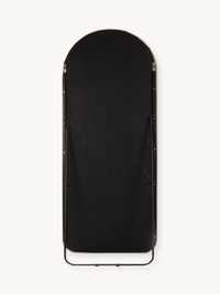 Rear view of arched full-length mirror showing black fabric backing, silver hardware clips, and black metal floor stand br…