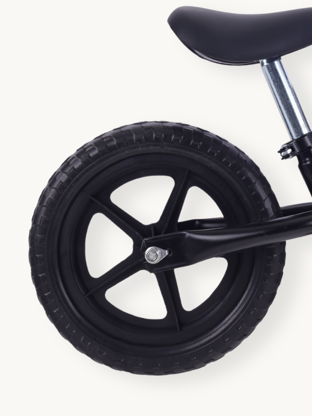 Close-up of rear wheel area showing black five-spoke plastic rim, knobby rubber tire tread, and padded saddle on chrome se…