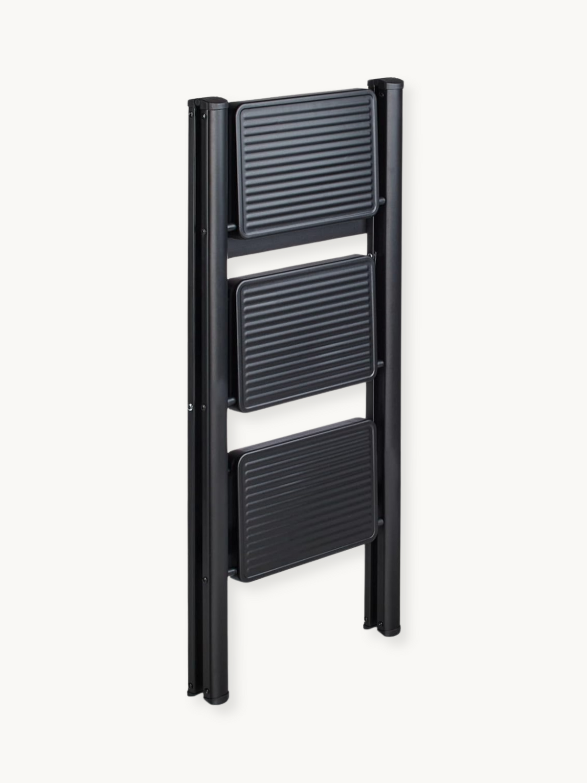 Black 3-step folding ladder collapsed flat, front angle view showing three ribbed dark grey steps between slim black metal…