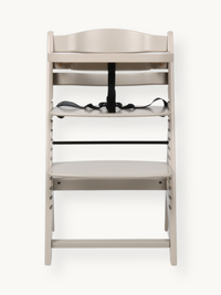Clay beige wooden highchair front view, black 5-point harness on seat, adjustable footrest below, no tray attached