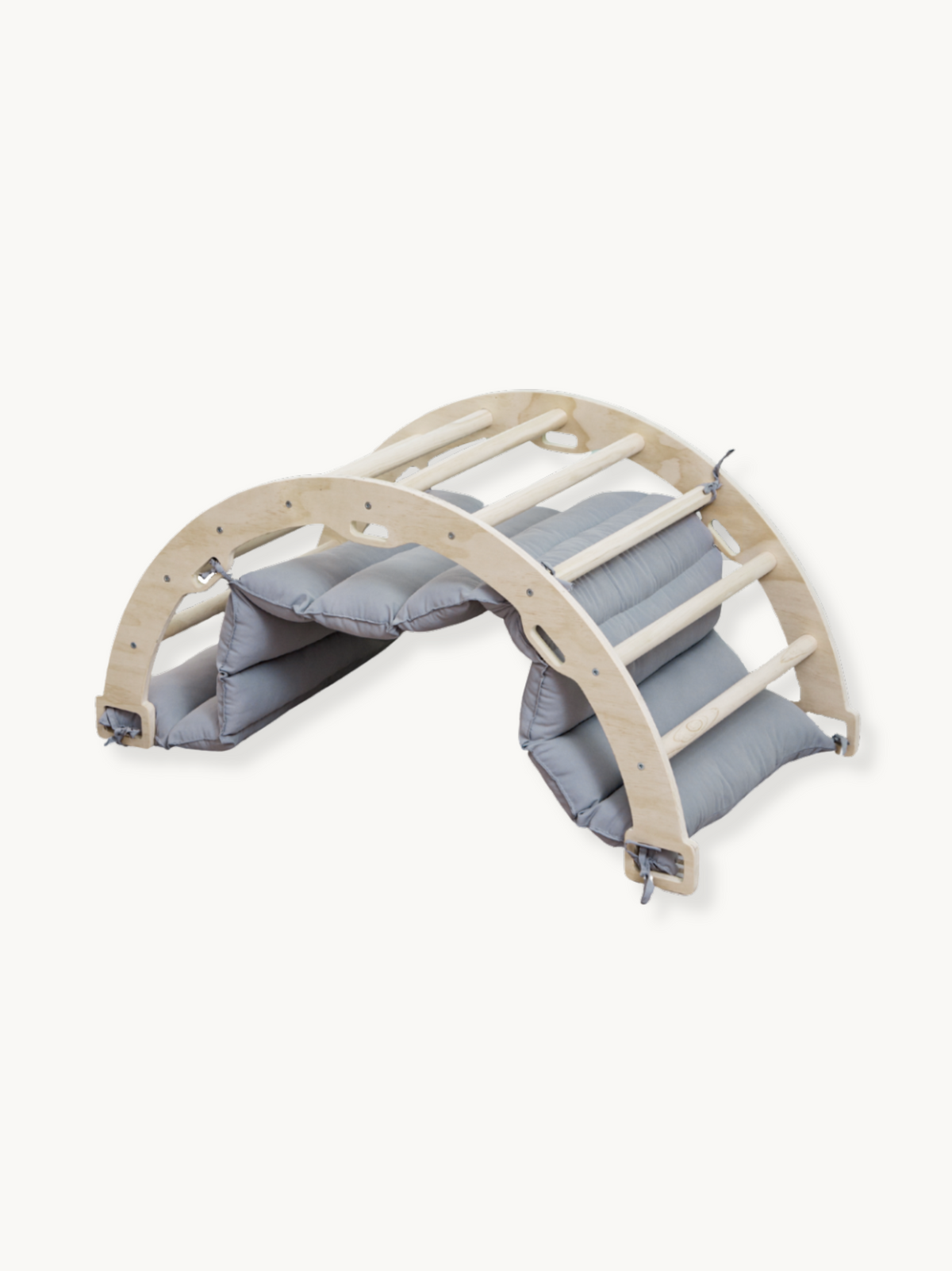 Natural wood climbing arch rocker with grey padded cushion fitted on both sides, angled three-quarter view on white backgr…
