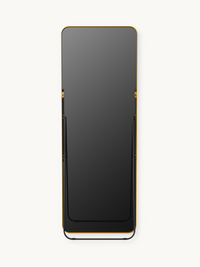 Rear view of full-length mirror with black panel, gold aluminium top edge, black metal floor stand, and gold wall-mount br…