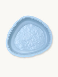 Light blue plastic balance stone, overhead view showing textured non-slip base and rounded triangular shape, on white back…