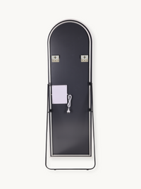 Back view of arched full-length LED mirror on black metal easel stand, showing two wall-mount brackets and white power cab…