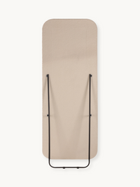 Rear view of Felis standing mirror flat, showing beige teddy fabric back and folded black metal support frame, white backg…
