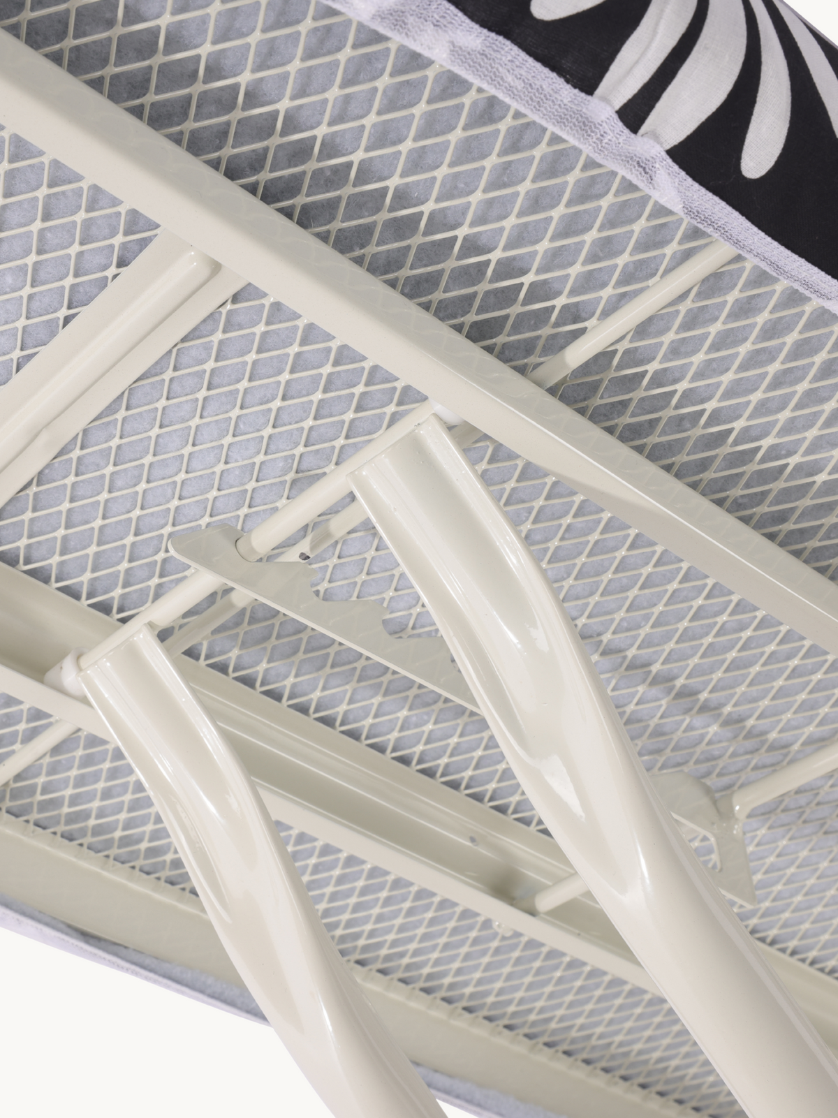 Close-up underside view of ironing board showing cream steel frame, mesh surface, and folding leg joint mechanism