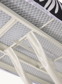 Close-up underside view of ironing board showing cream steel frame, mesh surface, and folding leg joint mechanism