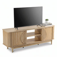 Light oak TV stand styled with a large flat-screen TV, stacked books and small succulent on top, open shelves and ribbed d…