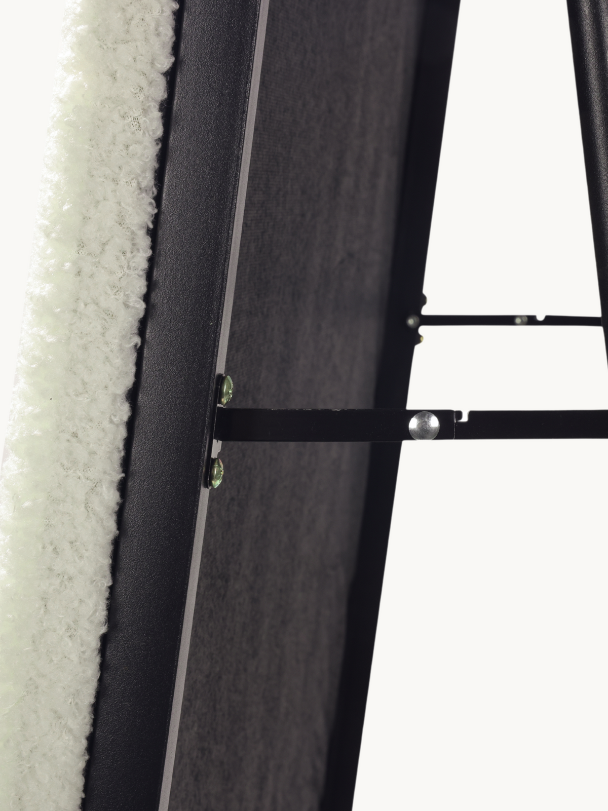 Close-up of white teddy fabric upholstery and black metal support hardware on the back of an oval standing mirror frame