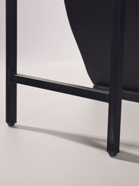 Close-up of black wooden frame base showing two square legs joined by a horizontal stretcher with small rubber feet