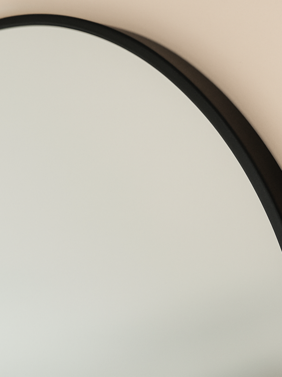 Close-up of upper-left quadrant showing slim black metal frame edge and flat mirror surface detail