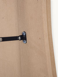 Close-up of black metal T-bracket with silver screws securing the stand to the taupe suede velvet-covered back panel of th…