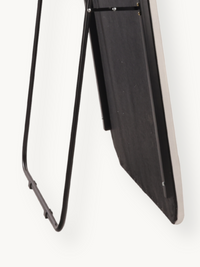 Back view of white suede velvet oval standing mirror showing black wood backing, silver screws, and black metal A-frame su…
